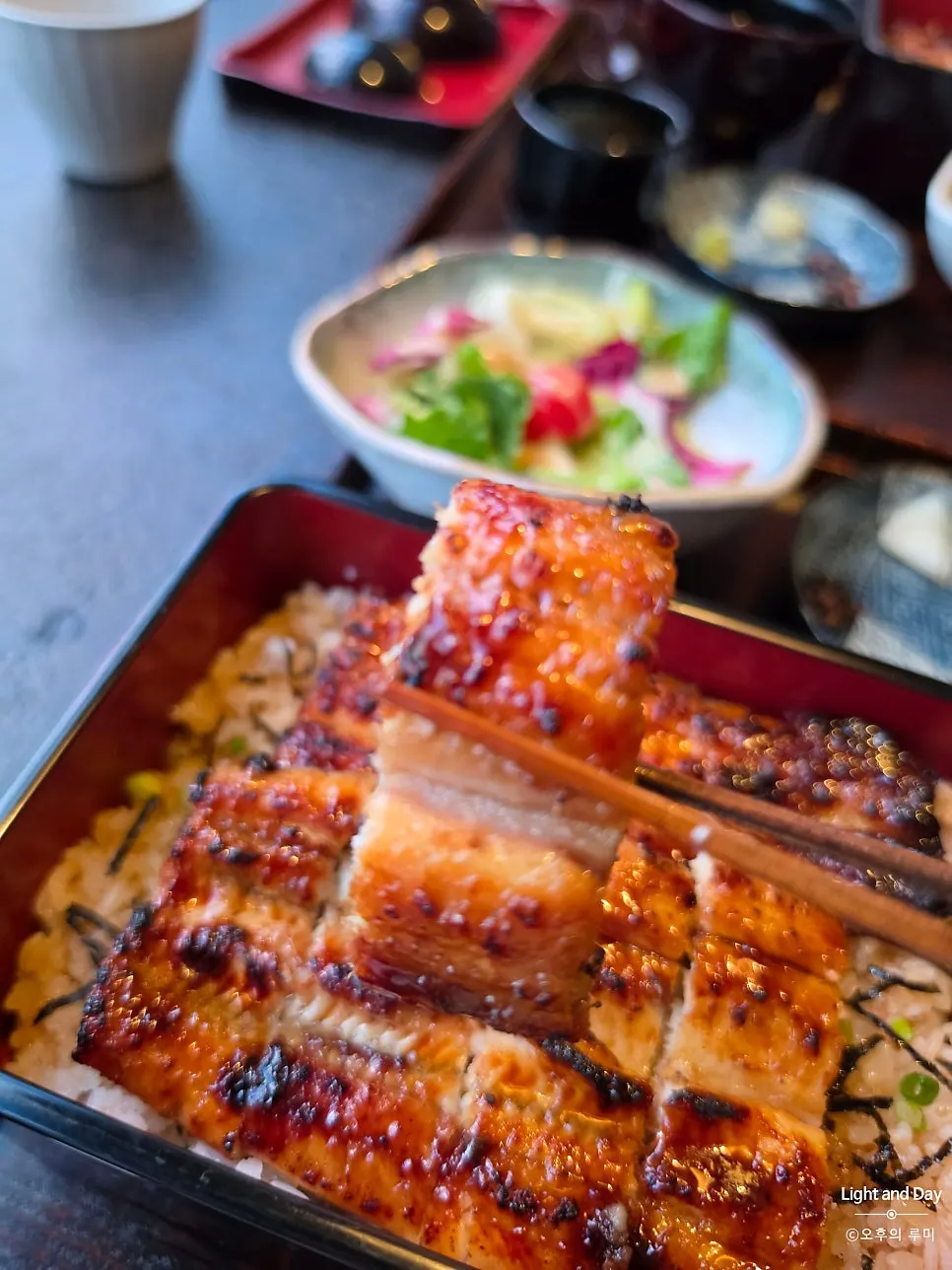 A piece of Manmok's eel lifted with chopsticks
