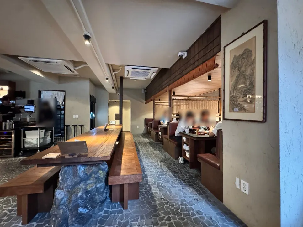 Natural stone boulder and solid-wood communal table in the center of Manmok's hall