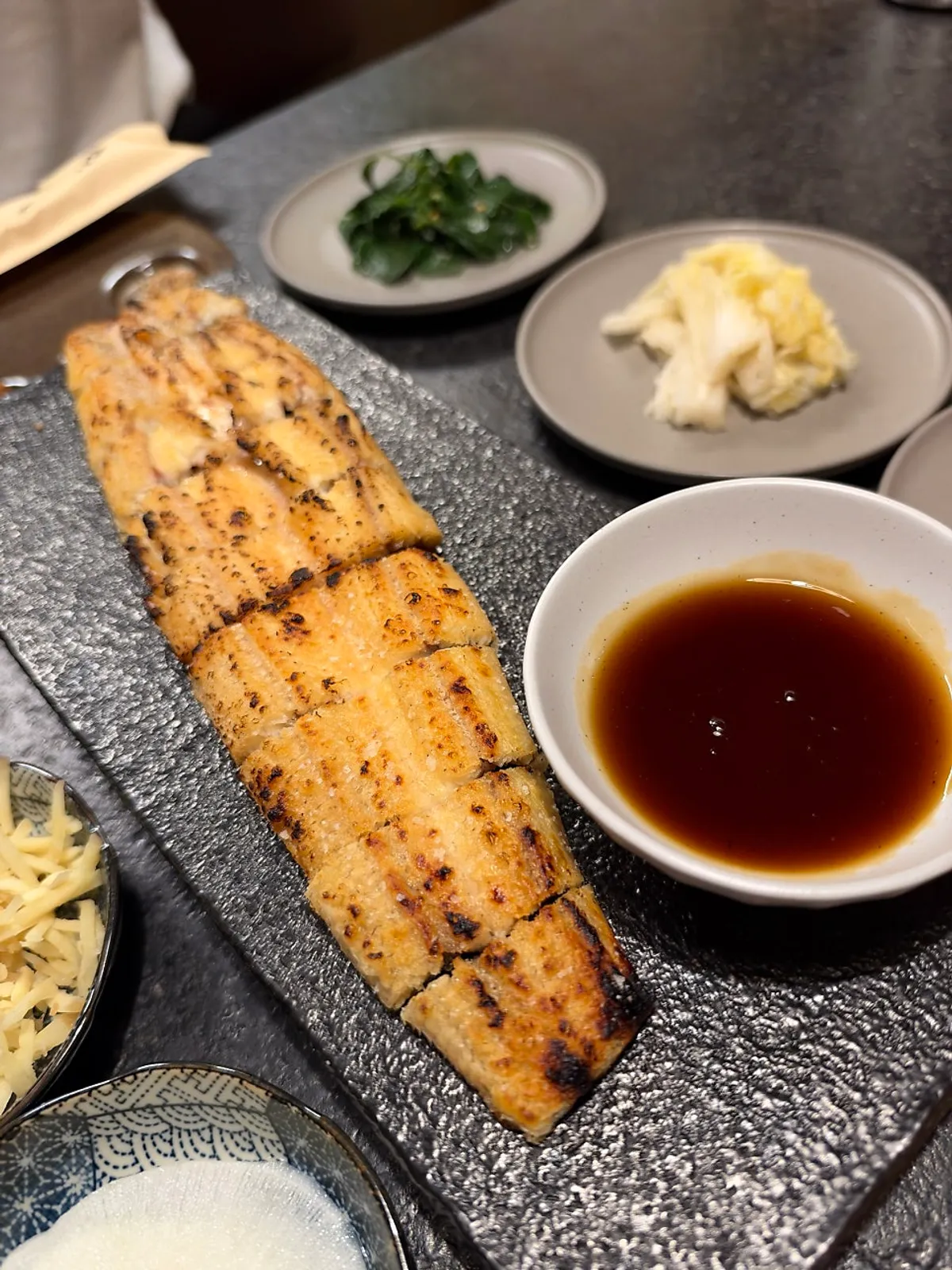 A piece of grilled eel topped with sancho pepper and garnishes