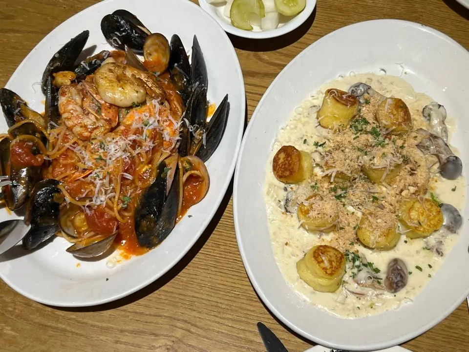 Table setting with creamy mushroom gnocchi and tomato seafood pasta