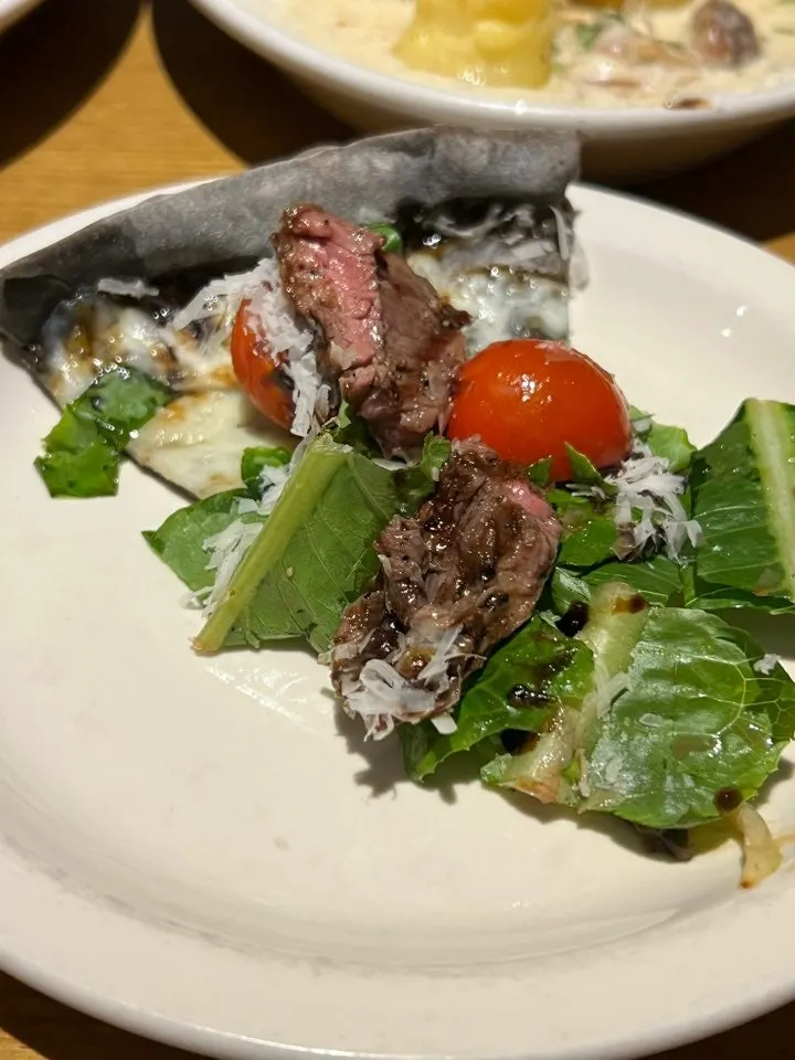 Slice of steak pizza showing thick cuts of meat