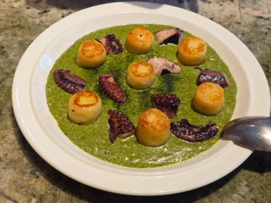 A plate of gnocchi topped with gim pesto and whole octopus