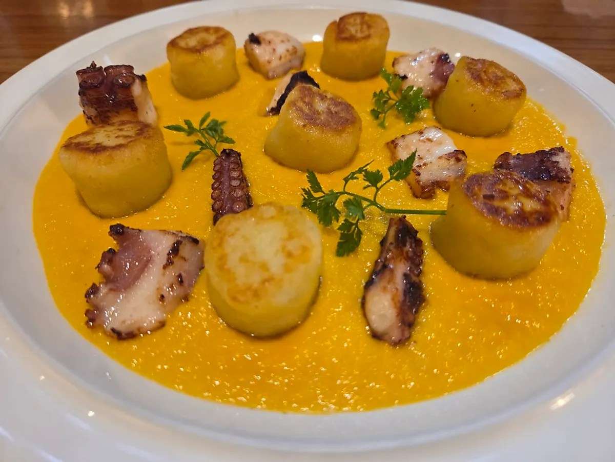 A plate of carrot purée octopus gnocchi