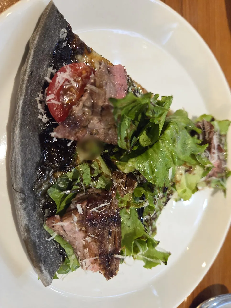 Pizza topped with steak, romaine, and cherry tomatoes