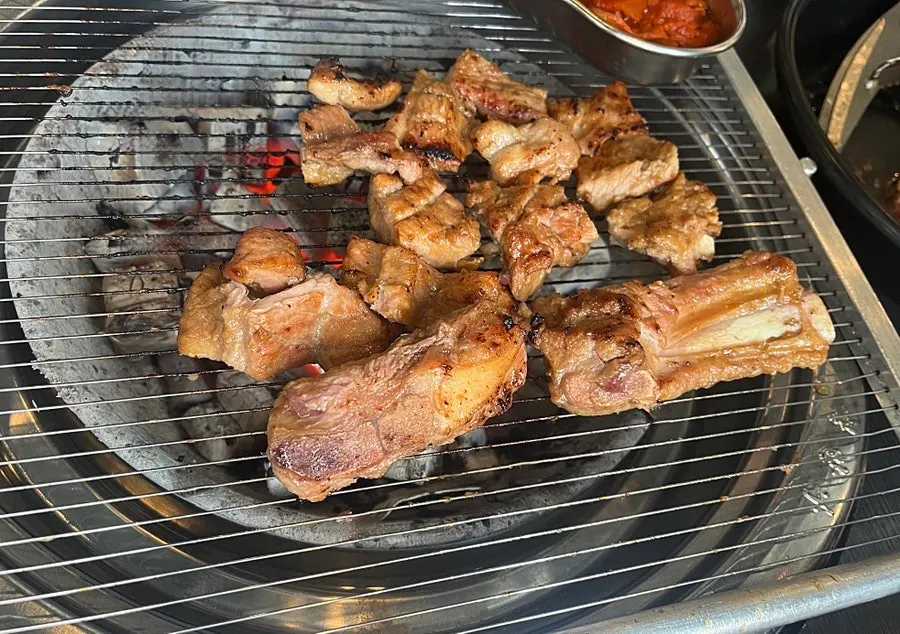 Marinated galbi placed on the grill over charcoal