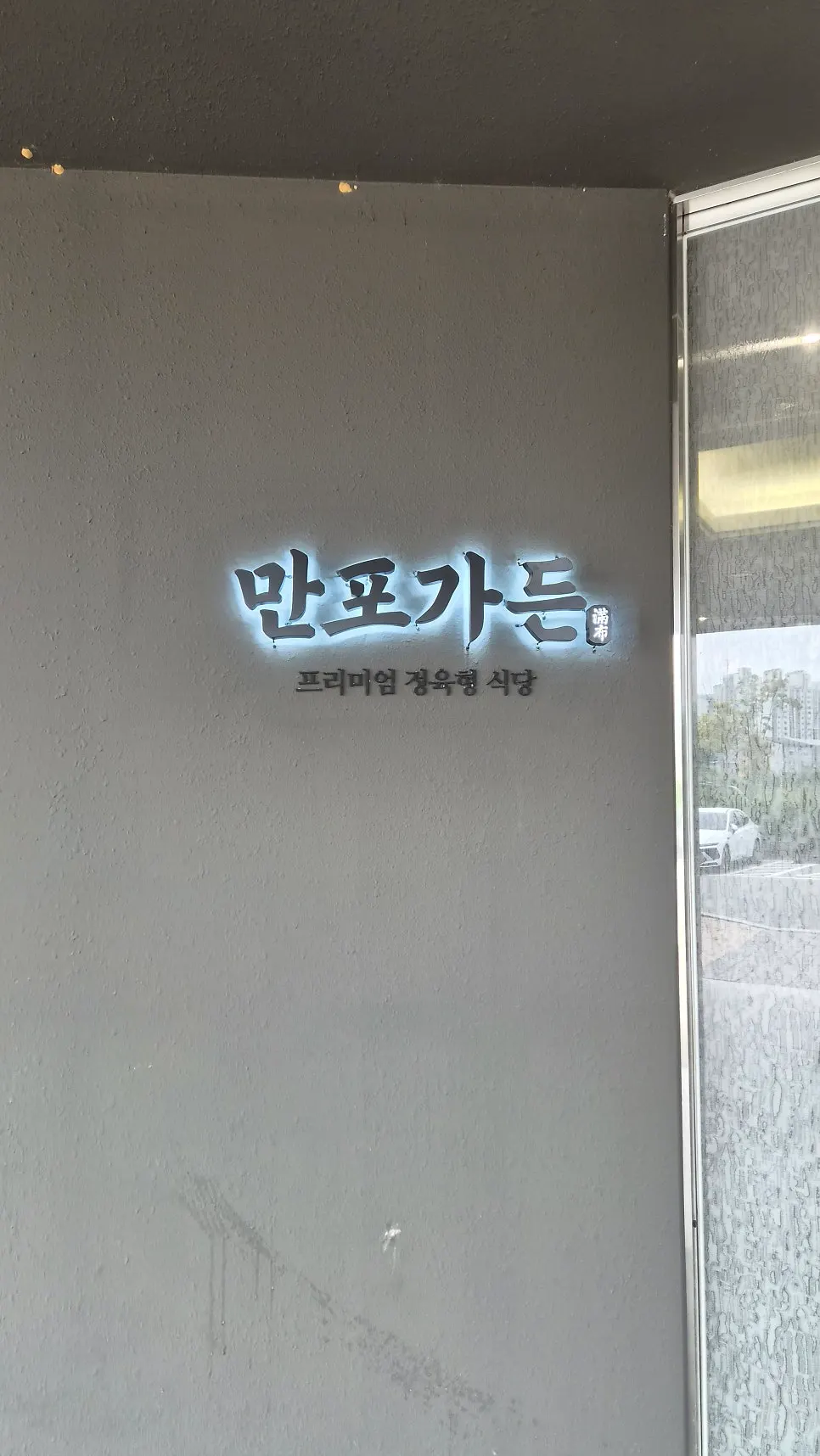 Premium butcher-style restaurant logo and phrase on the entrance wall at Manpo Garden