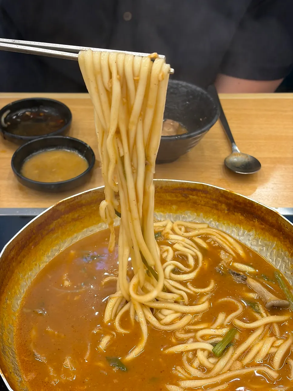 Chewy kalguksu noodles lifted out of the broth