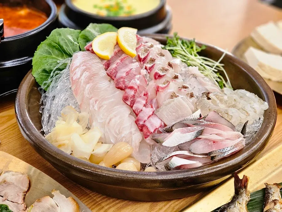 Primer plano de la mesa servida en Jaecheoldameun Mapo Bada