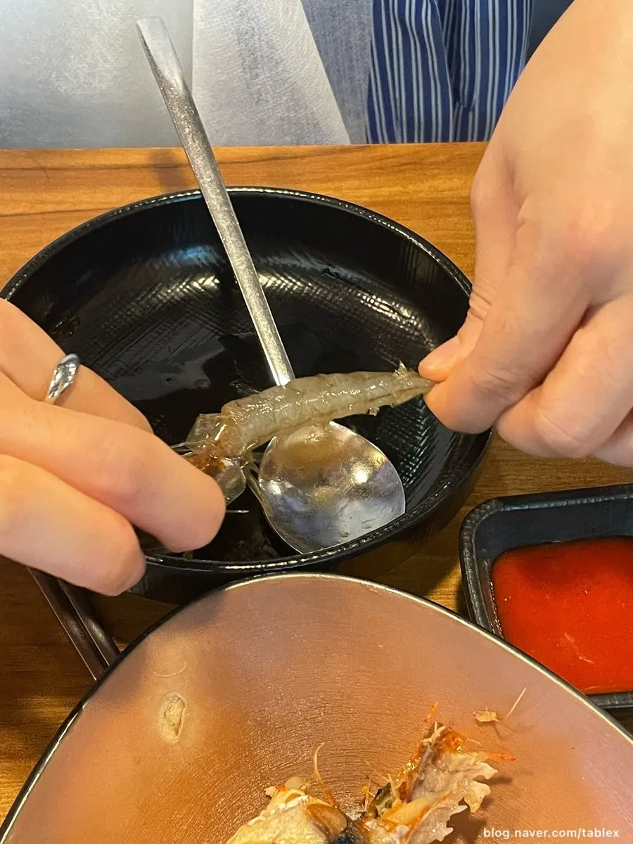 Hands peeling the shell off a soy sauce shrimp