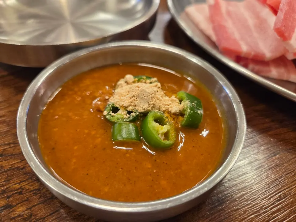 Plate of ssamjang topped with soybean powder alongside lettuce and garlic