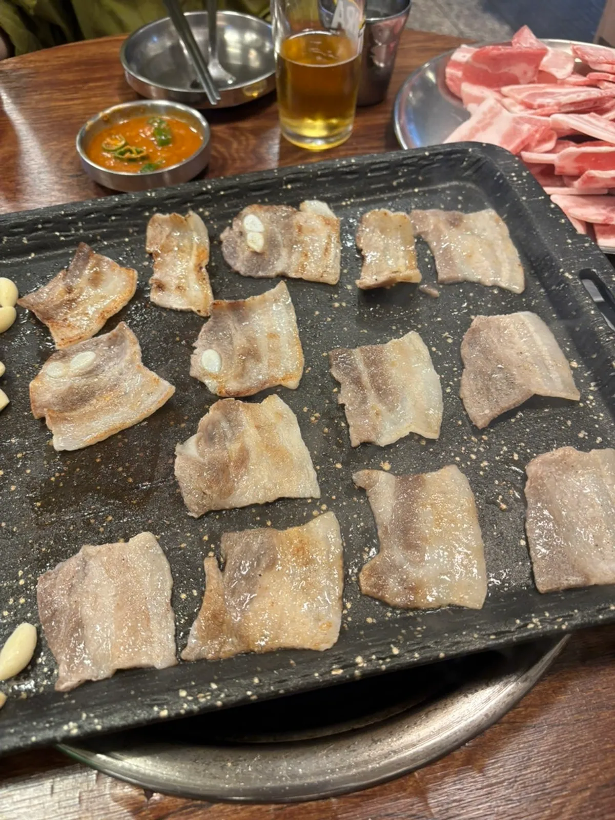 불판에서 구워지는 냉삼과 맥주 한 잔