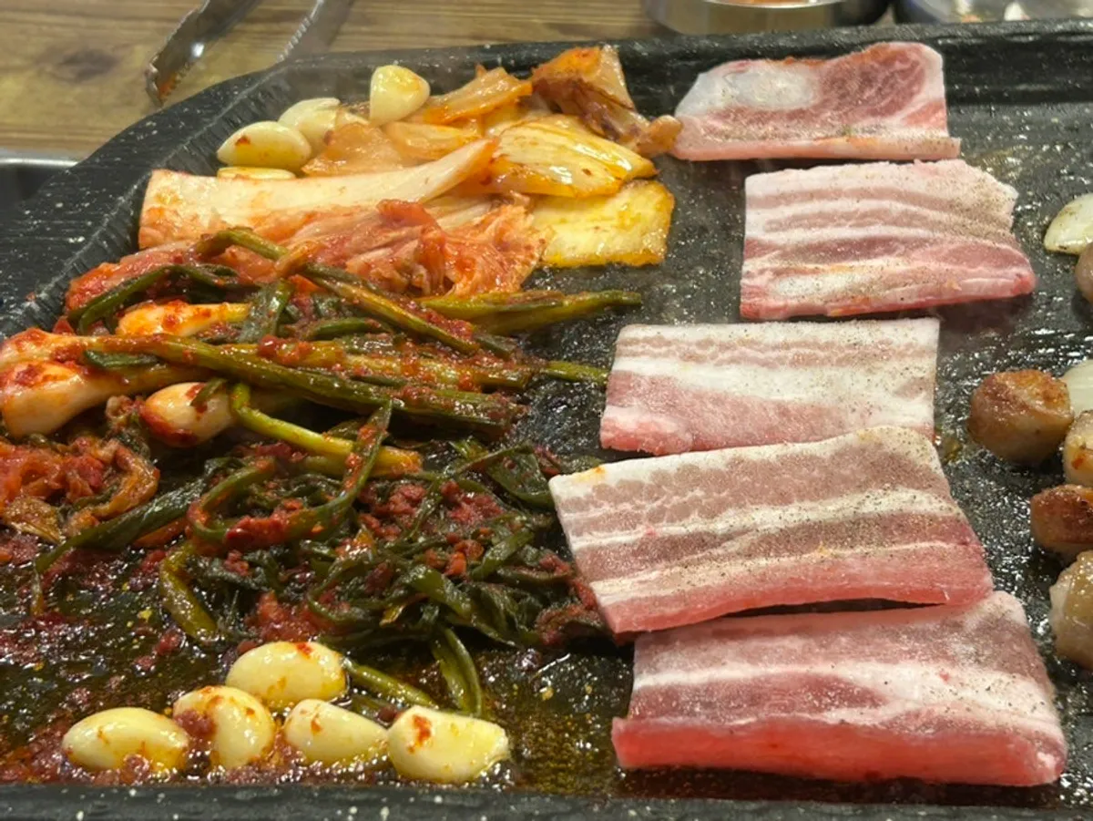 A piece of pork belly topped with green onion kimchi