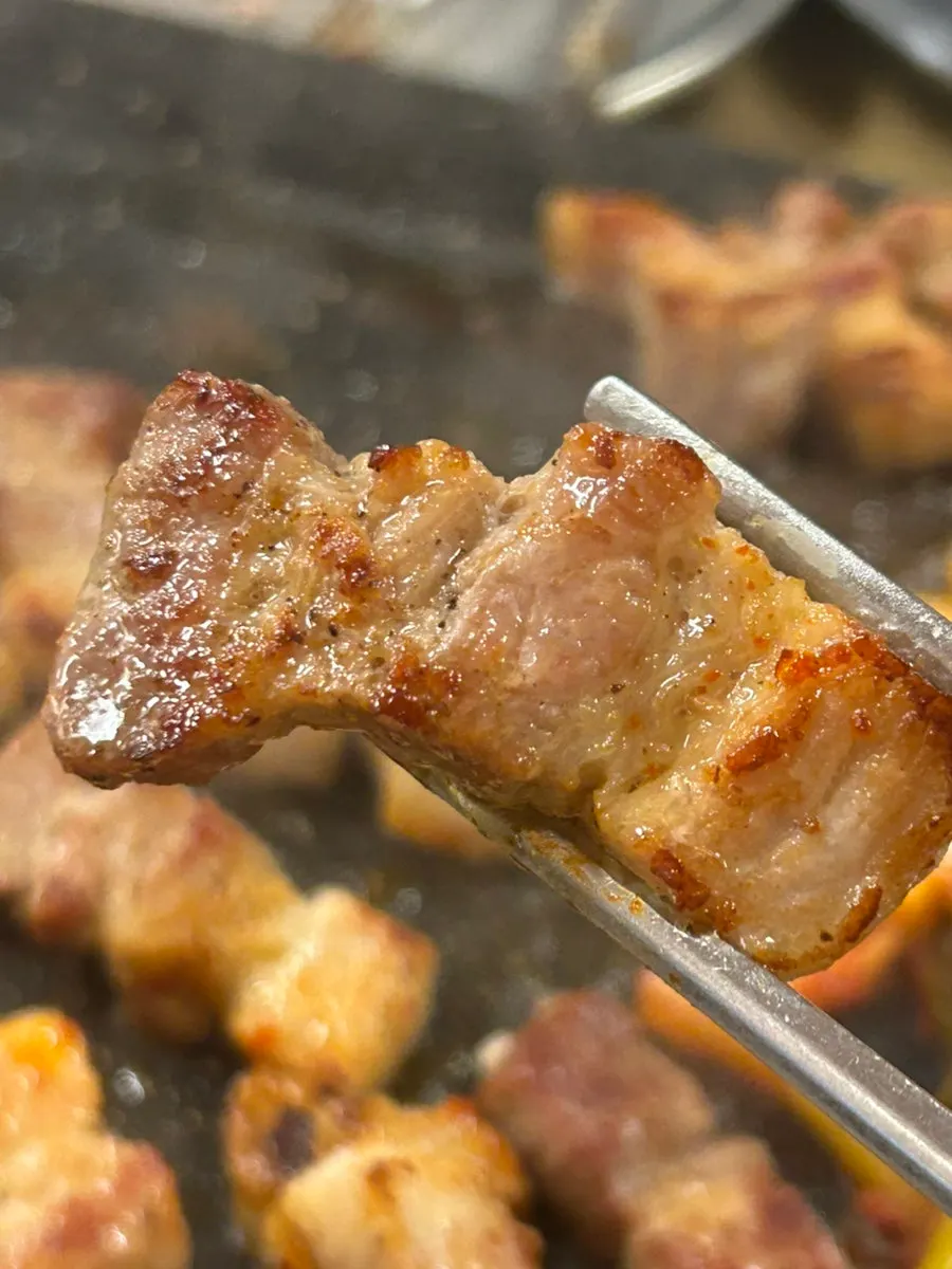A piece of pork belly dipped in the signature sauce