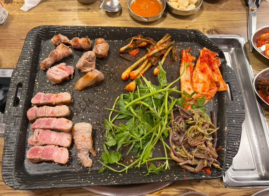 Pork belly on the grill with kimchi, fernbrake, and minari