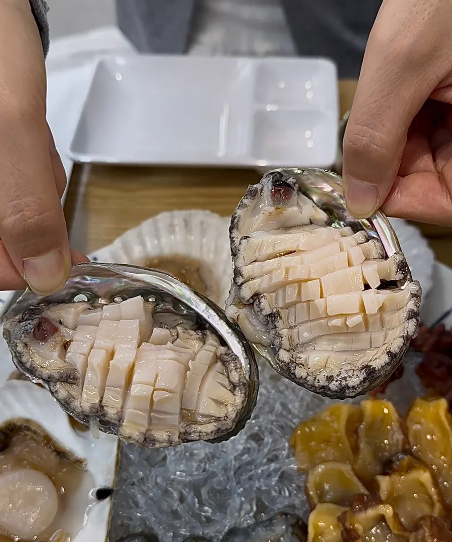 Close-up of a piece of seafood picked up with chopsticks
