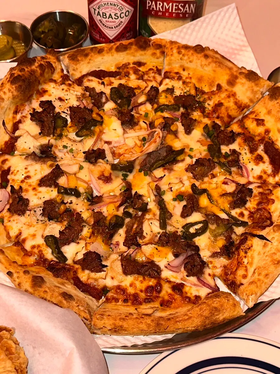 Table scene of pizza and chicken being enjoyed together