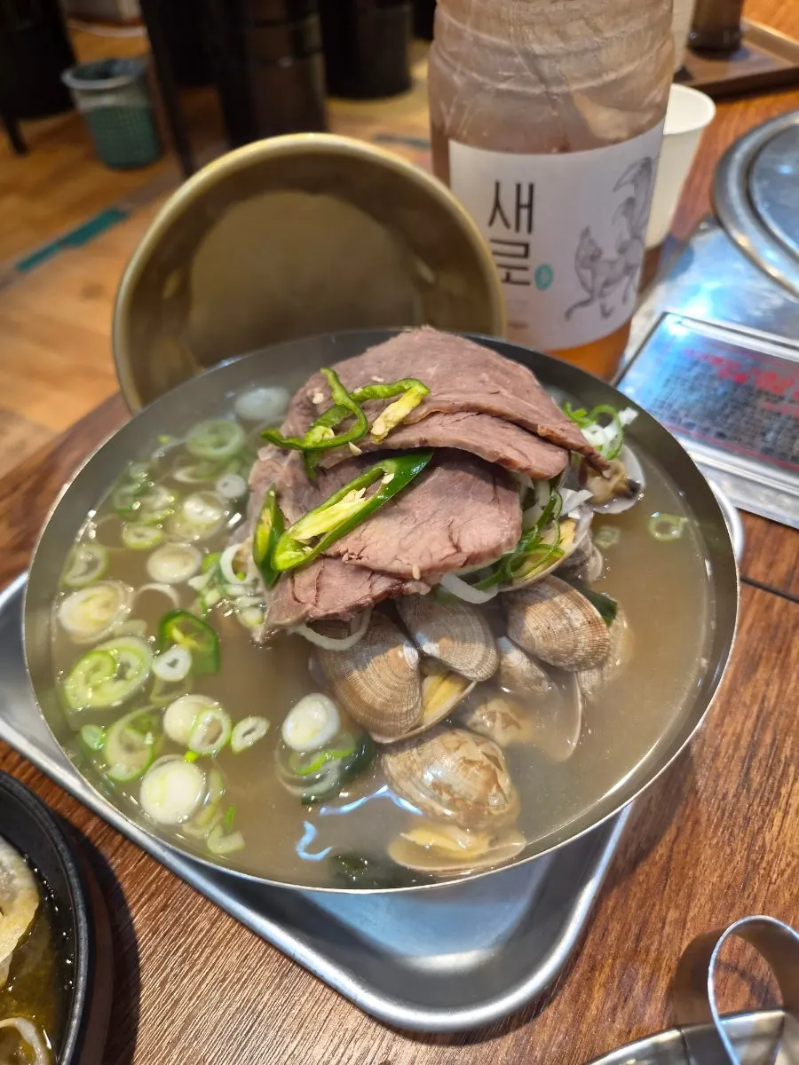 소고기와 바지락 건더기가 보이는 국밥 국물