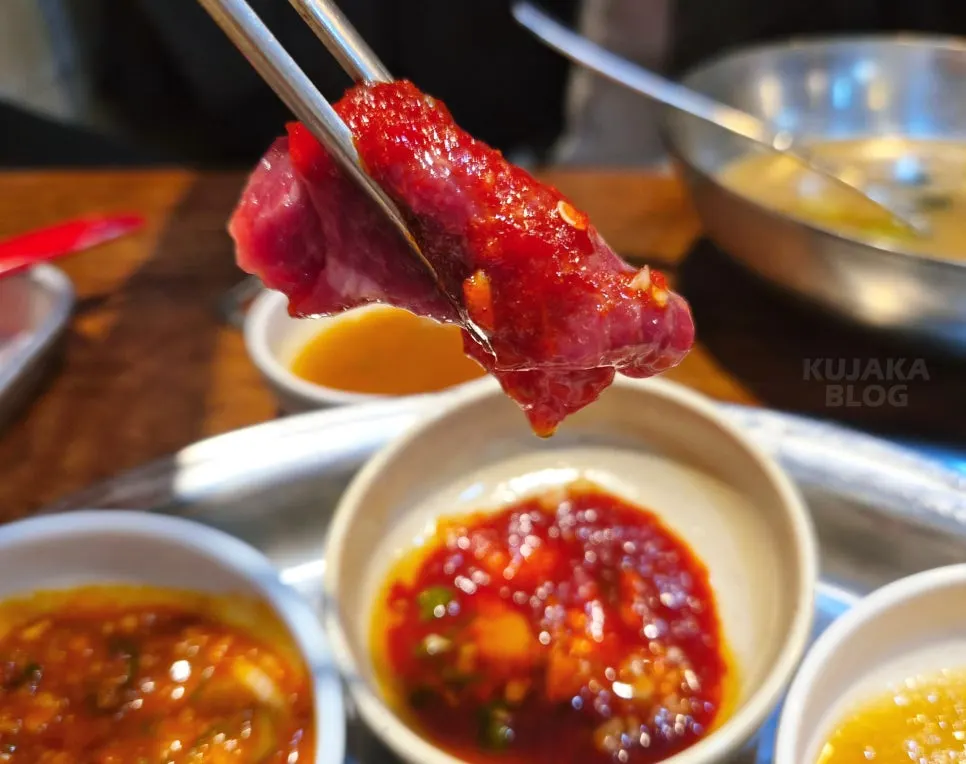 A piece of raw beef sashimi dipped in sauce