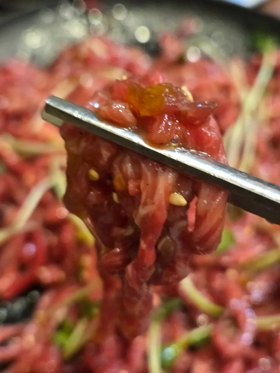 Picking up raw beef mixed with egg yolk