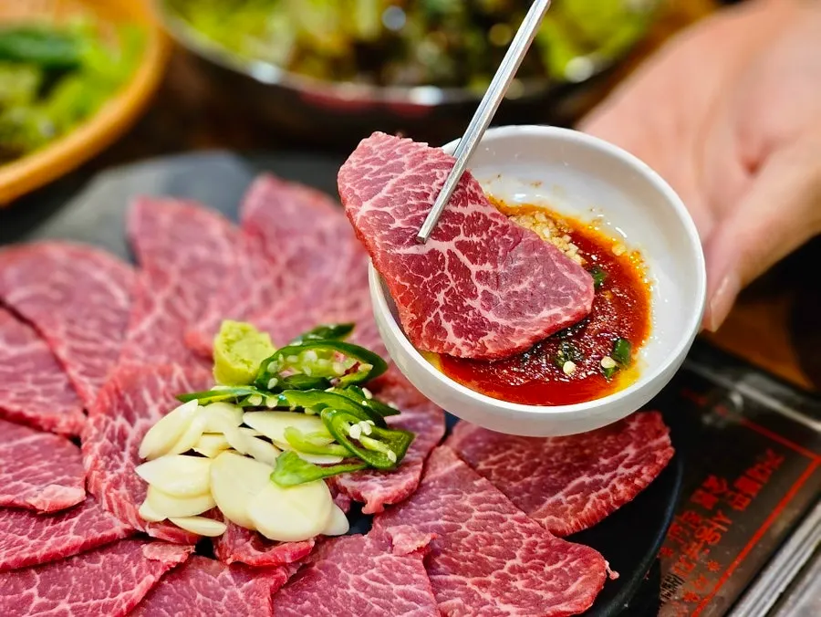 A piece of yuksashimi dipped in special seasoned sauce