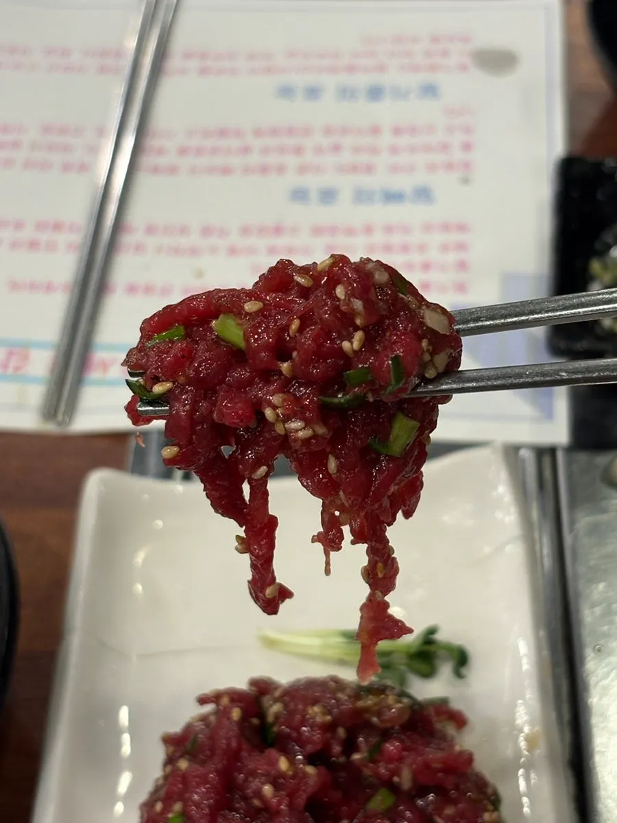 Chopsticks lifting a piece of horse yukhoe