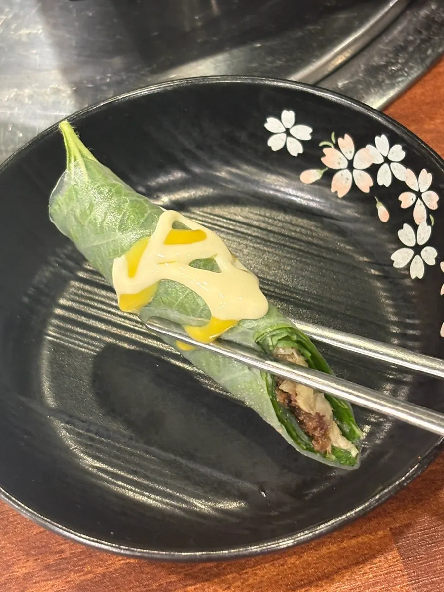 A piece of horse sushi picked up with chopsticks