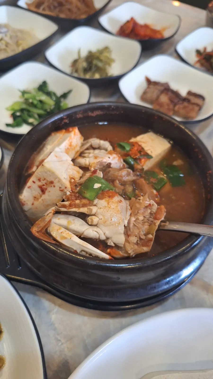 A bowl of seafood doenjang jjigae with crab
