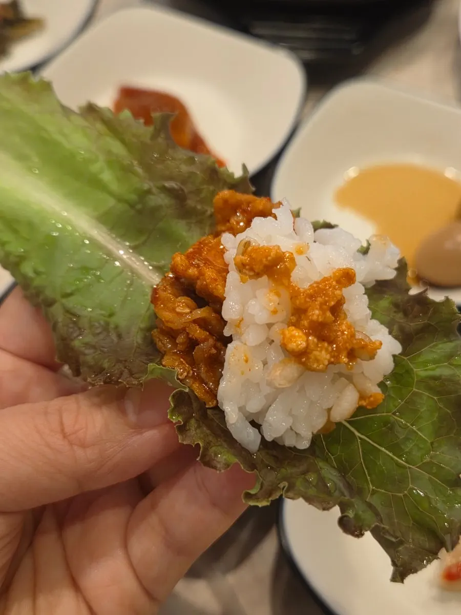 A wrap vegetable topped with stir-fried pork and rice