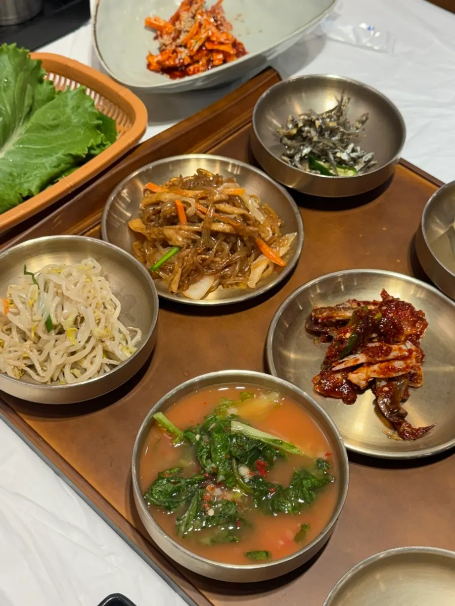 Side dishes at Yun Sikdang including seasoned squid, japchae, and steamed egg