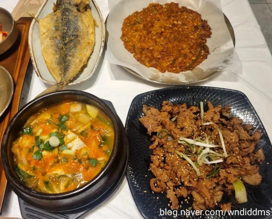 Table with grilled bulgogi, grilled fish, and kimchi pancake