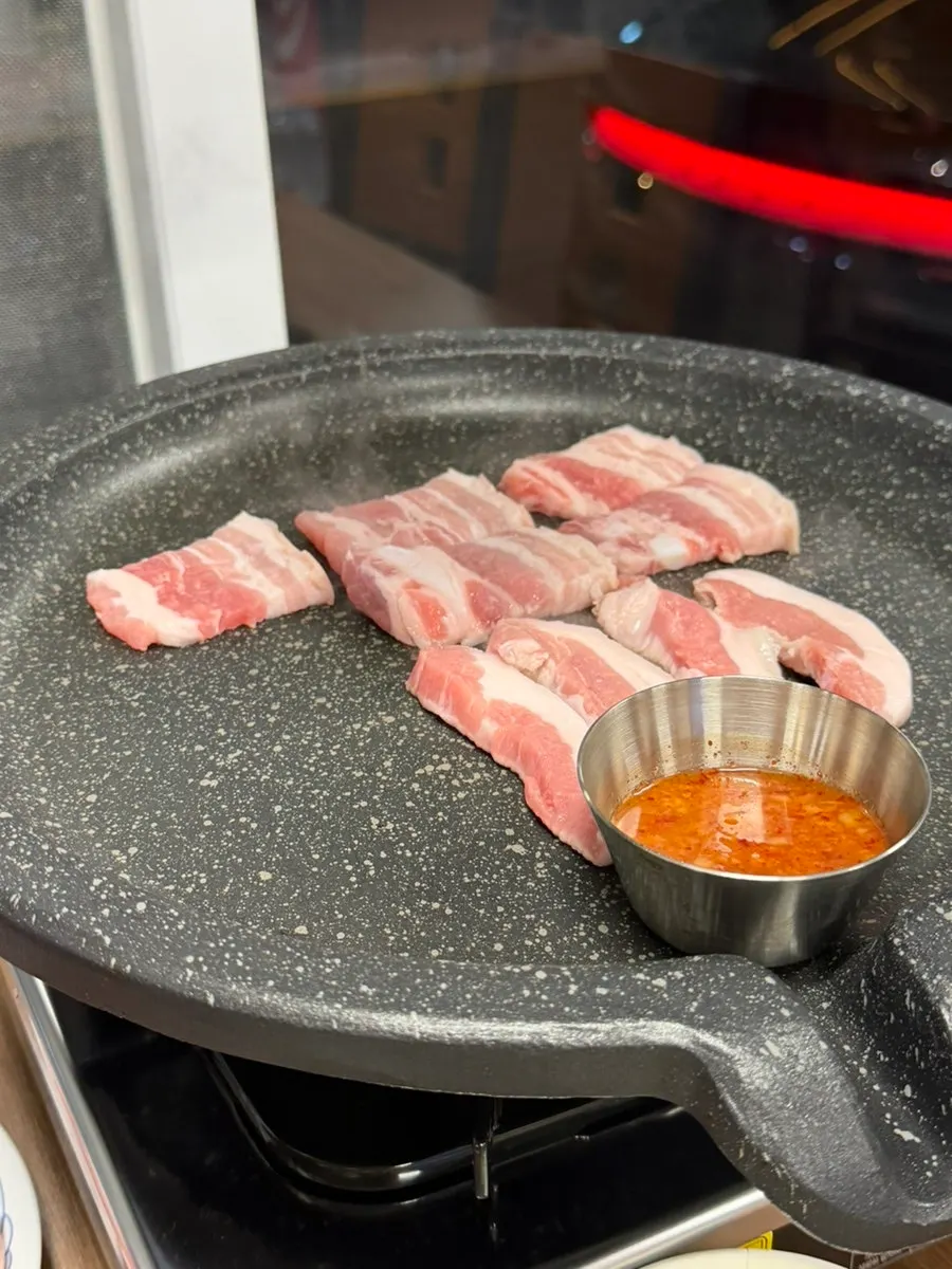 Parrilla llena de ogyeopsal, kimchi y patata