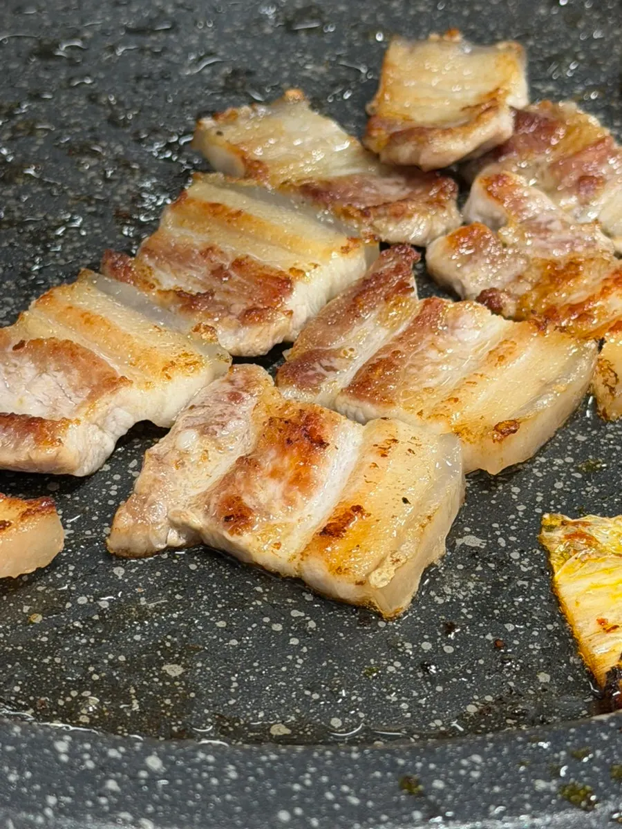 Kimchi y ogyeopsal dorándose en la parrilla