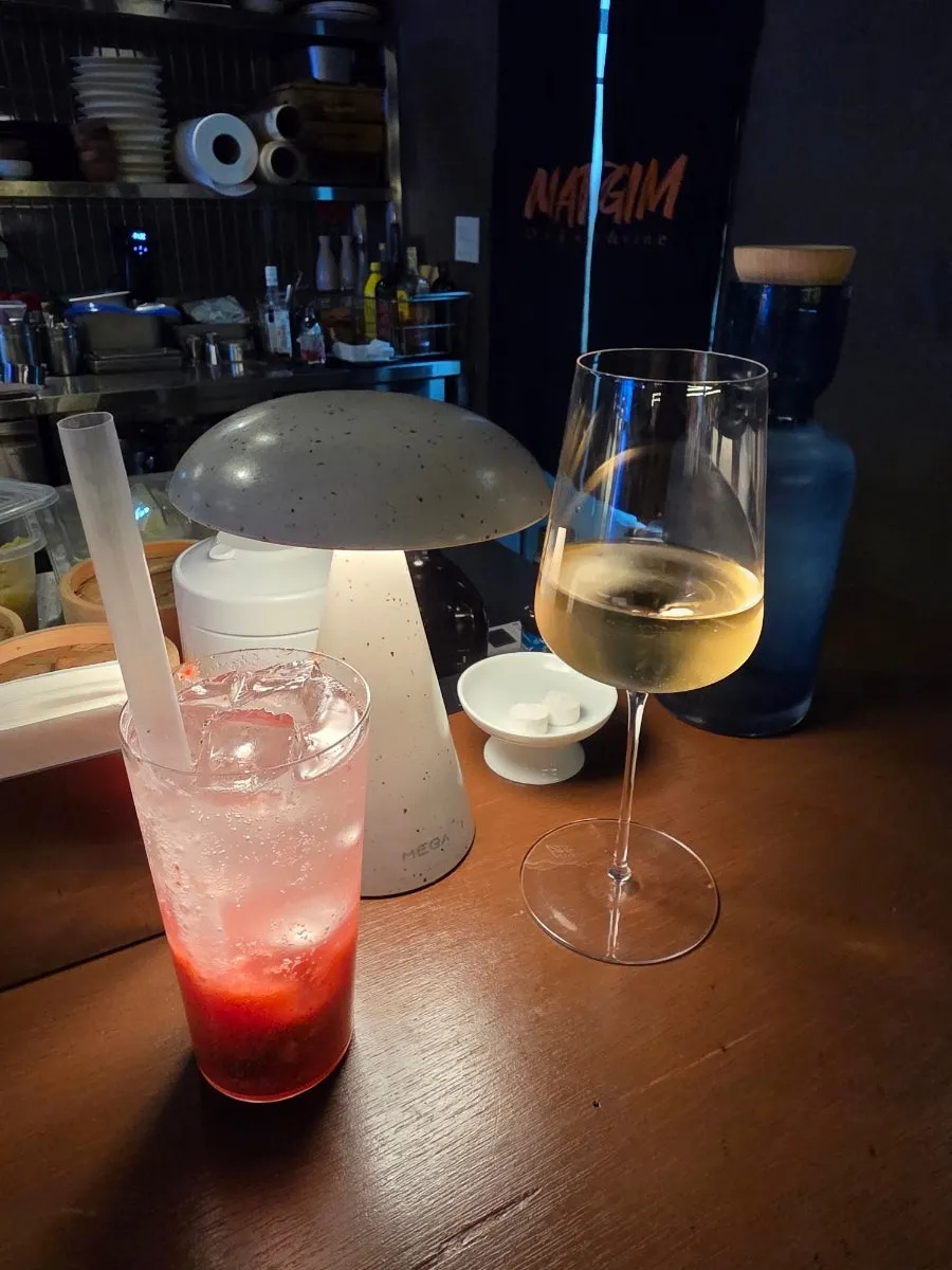 A glass of white wine and a strawberry mint seasonal ade