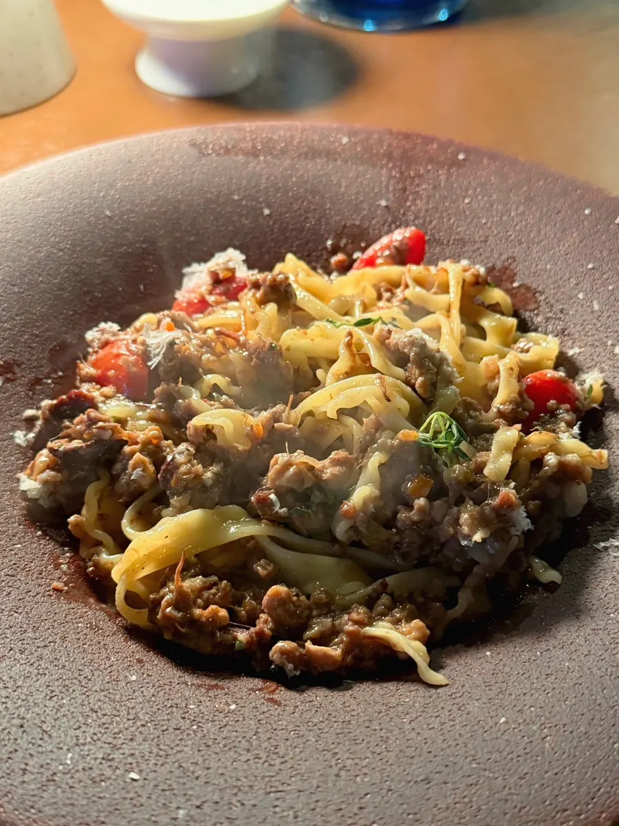 Close-up of wide pasta noodles coated in ragu sauce