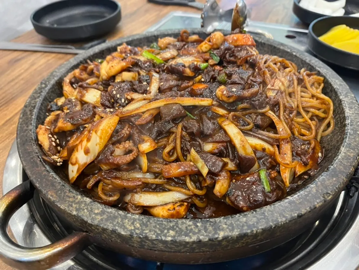 Jjukkumi stone jjajang piled high on the hot stone griddle