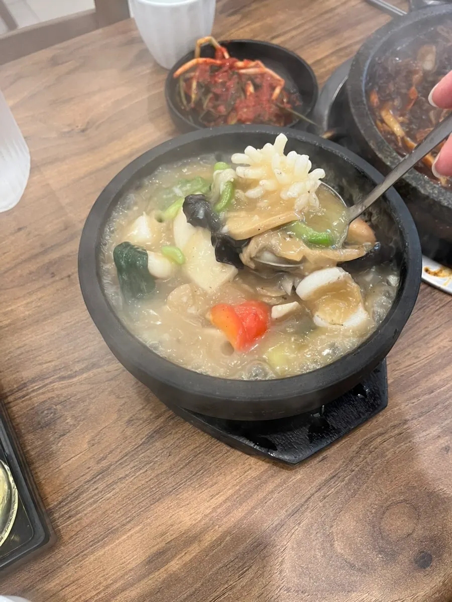 Table setting with jjukkumi stone jjajang and seafood scorched-rice soup