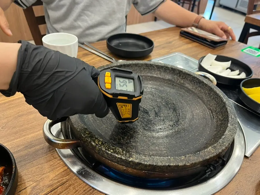 Staff checking the temperature of the stone griddle
