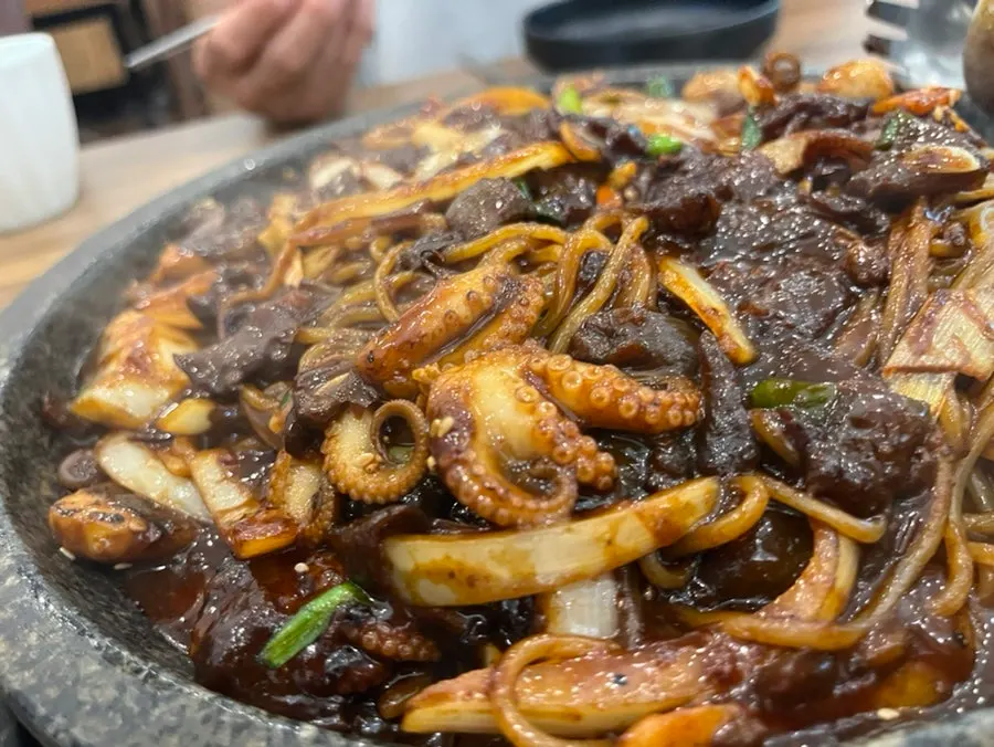 Jjajang sauce sizzling as it cooks on the stone griddle