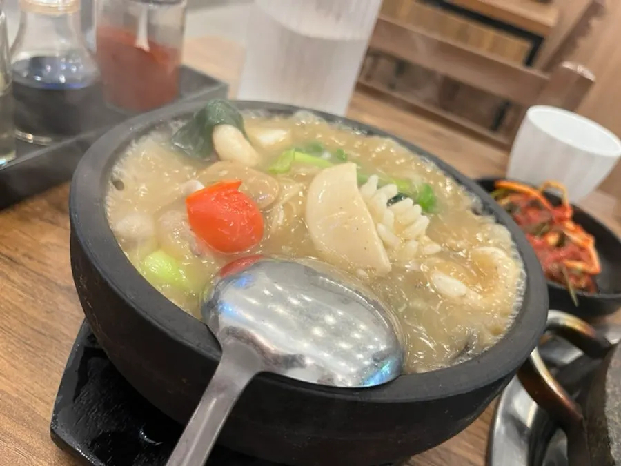 Hot seafood sauce being poured over the scorched rice