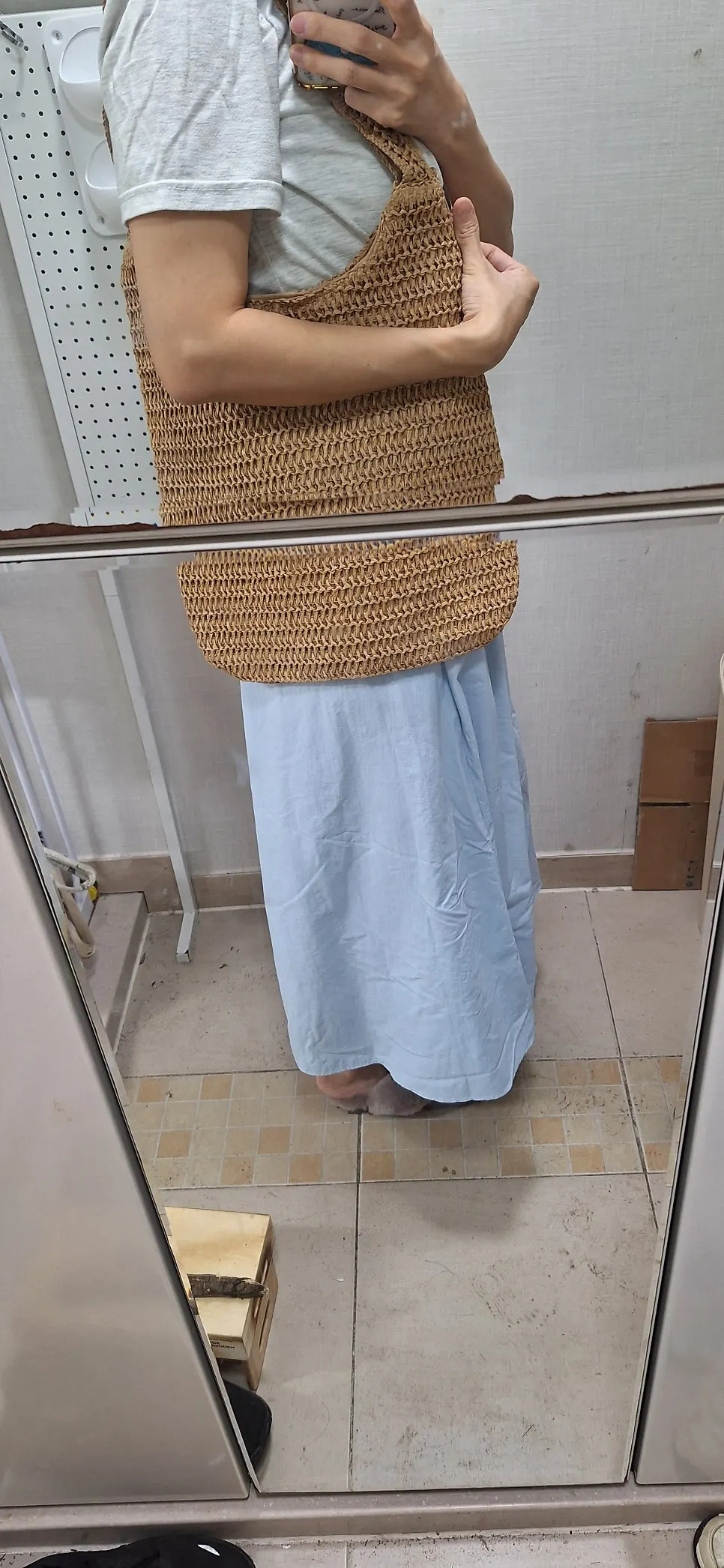 Side view of a long dress and large rattan shoulder bag