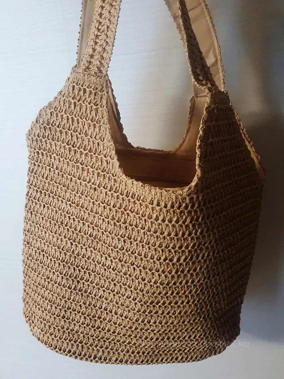 Slim rattan shoulder bag worn on the shoulder