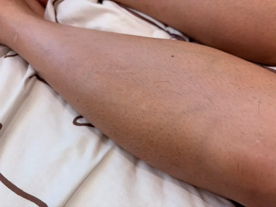Preparing to use tone-up milk on legs while sitting on a sofa