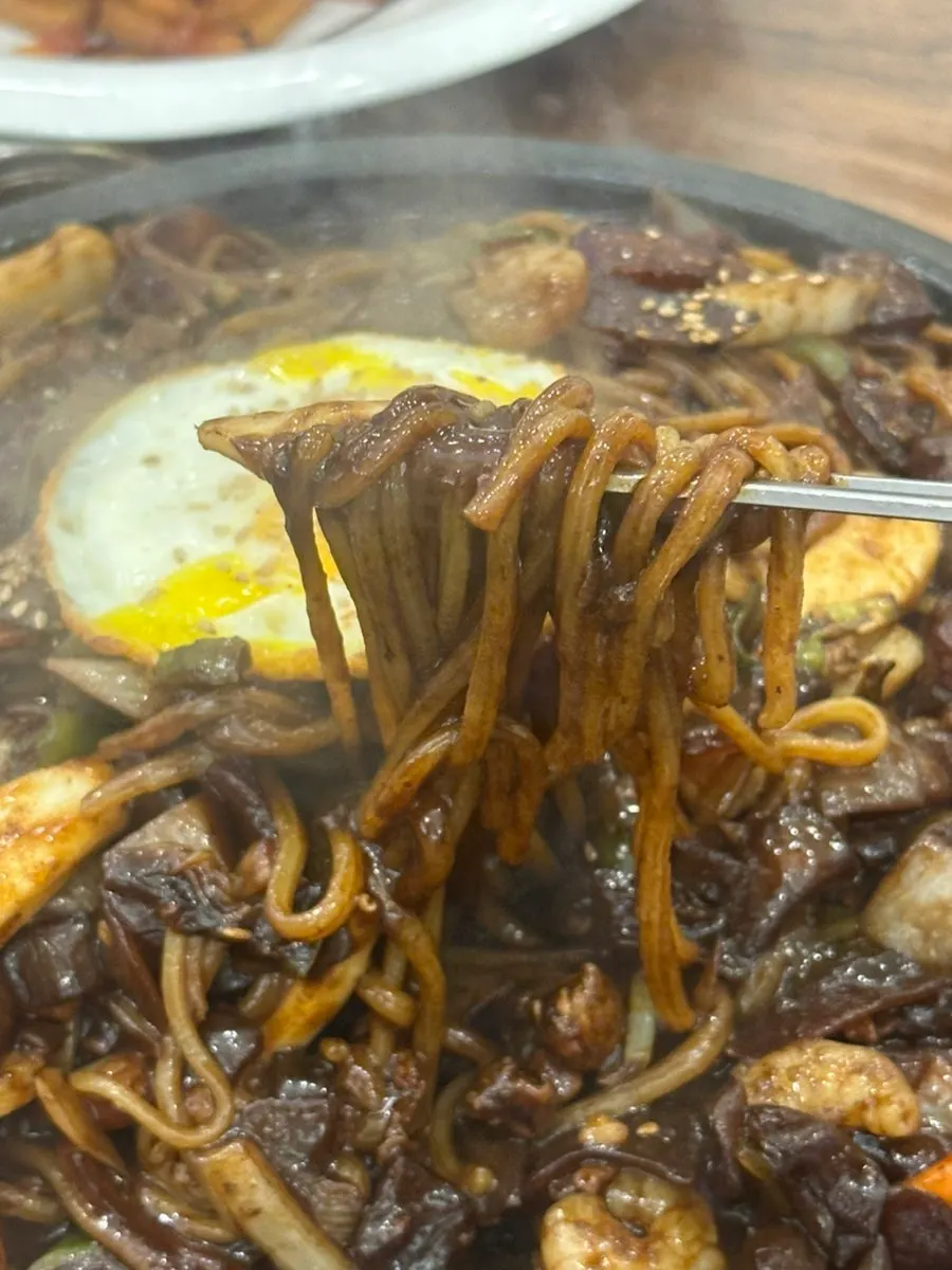 Close-up of sizzling stone-griddle jjajang