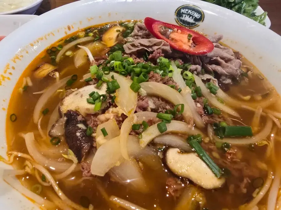 Table setting with spicy beef pho and nasi goreng