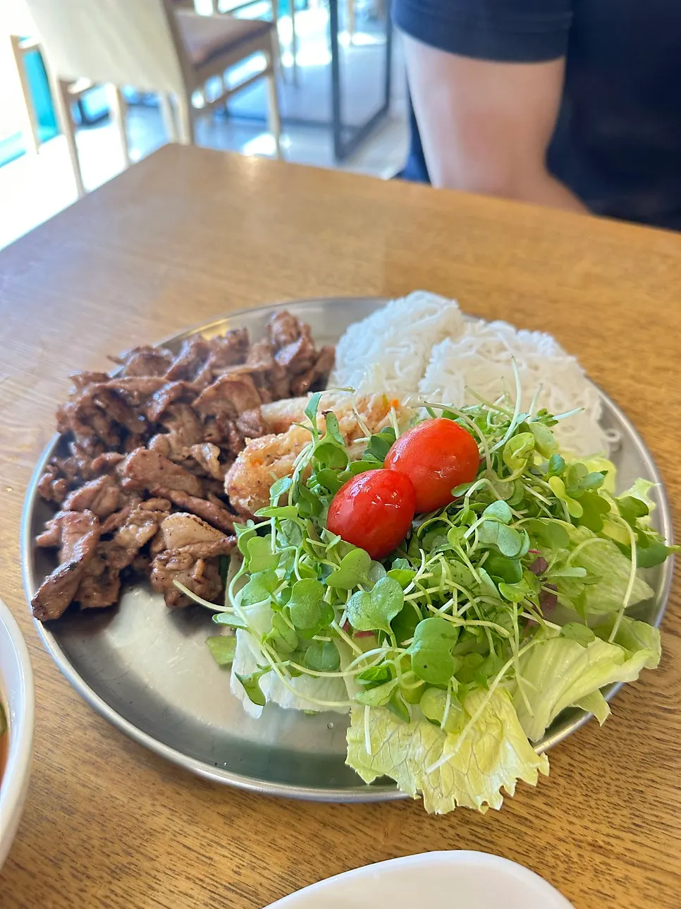 Plate of bun cha with grilled meat, lettuce, and spring rolls