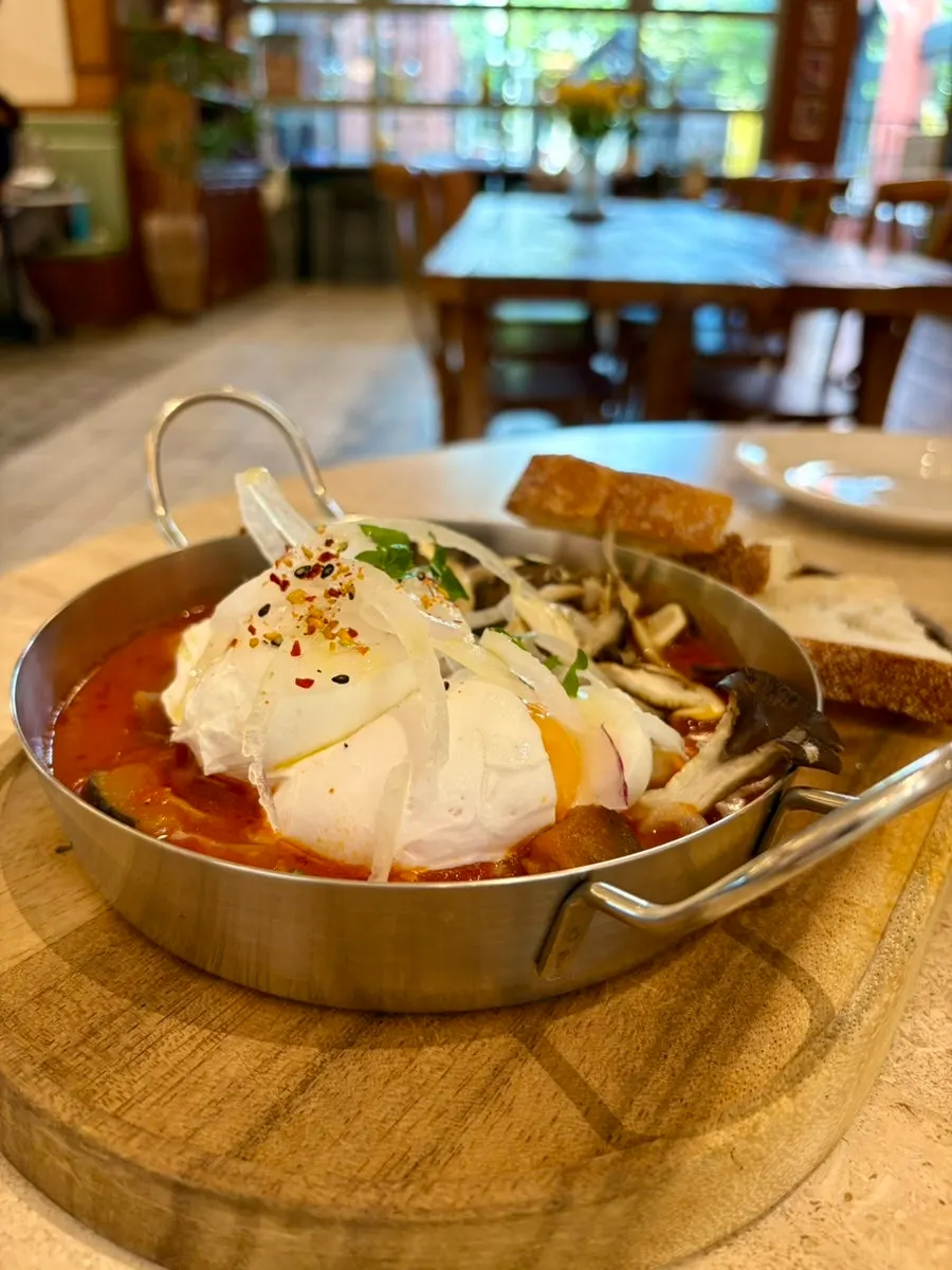Shakshuka topped with two poached eggs and mushrooms