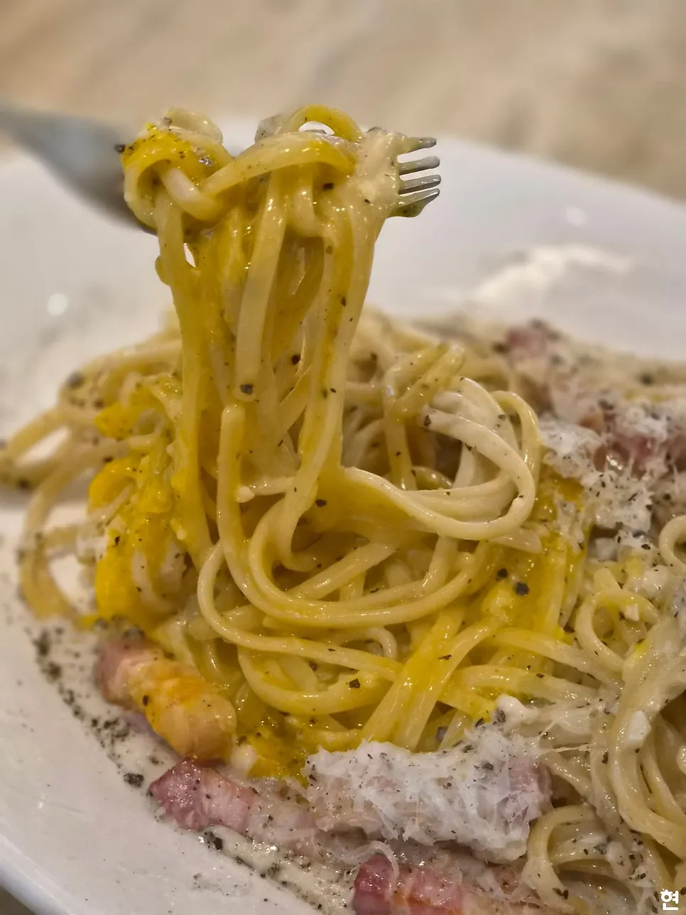 Carbonara topped with thick bacon and an egg yolk