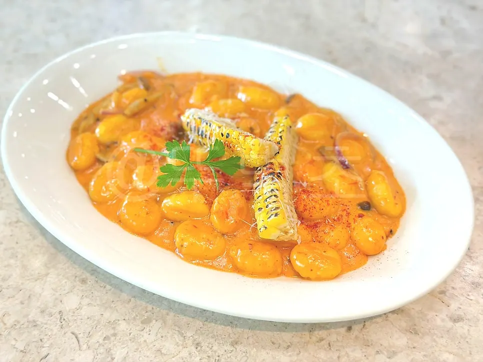 Potato gnocchi dish topped with corn kernels