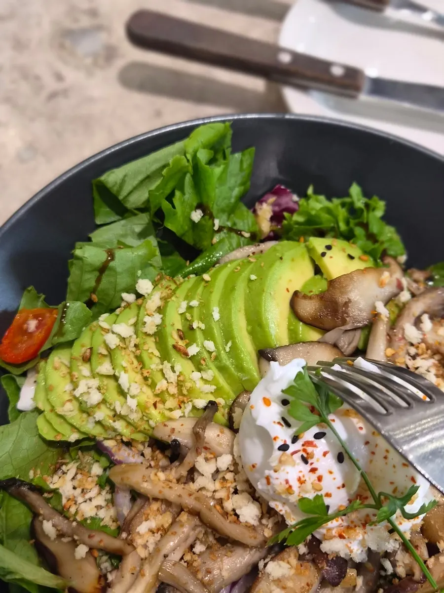 Close-up of the salad topped with avocado and poached egg