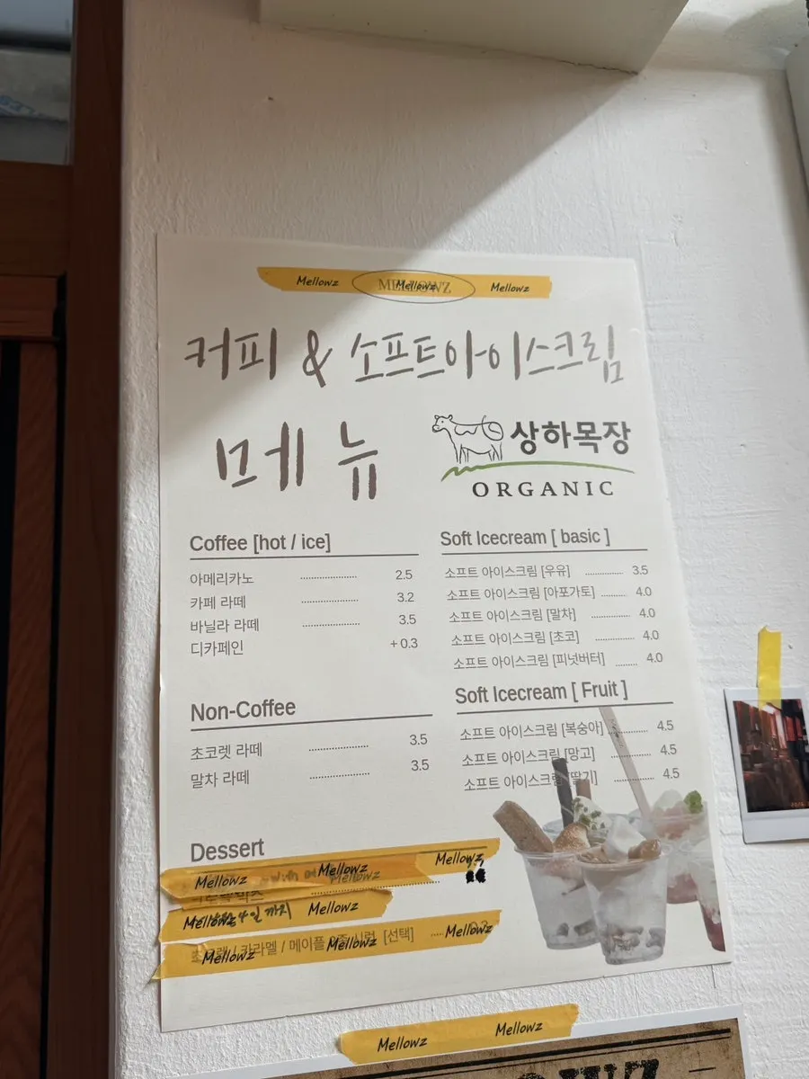 흰 필기체 영문 상호가 적힌 멜로우즈 벽면